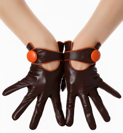A pair of dark brown  leather gloves with orange side button details, shown on a model's hands against a white background.